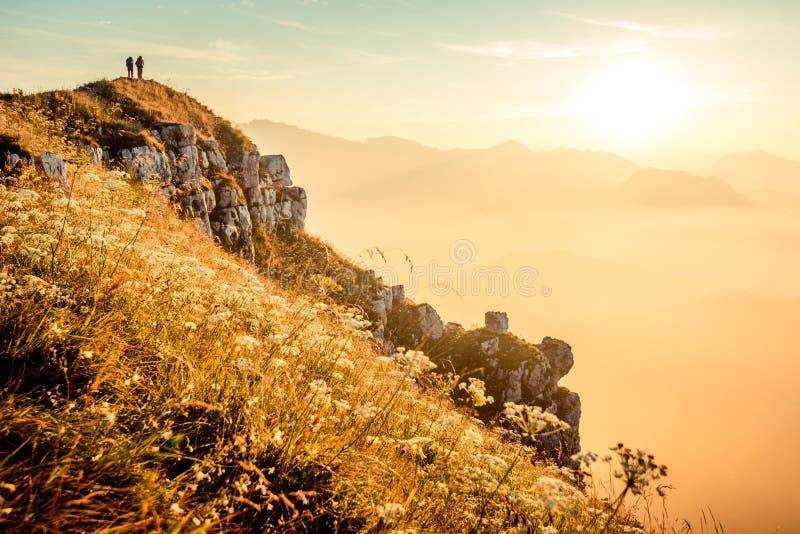 Hikers walking at sunrise on top of italian alps mountains