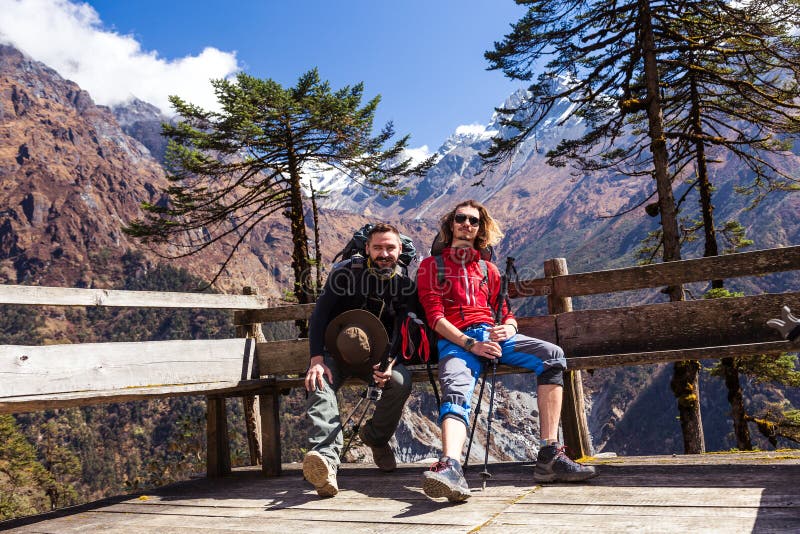 2 Hikers отдыхая на горе приютят сидеть на деревянном стенде стоковая фотография 2 Hikers отдыхая на горе приютят сидеть на деревянном стенде стоковая фотография