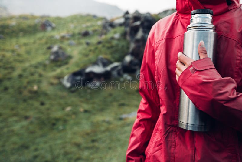Hiking Adventure Tourism Vacation Holiday Concept. Unrecognizable girl traveler holds a thermos in her hand Overview of a wild la royalty free stock image Hiking Adventure Tourism Vacation Holiday Concept. Unrecognizable girl traveler holds a thermos in her hand Overview of a wild la royalty free stock image