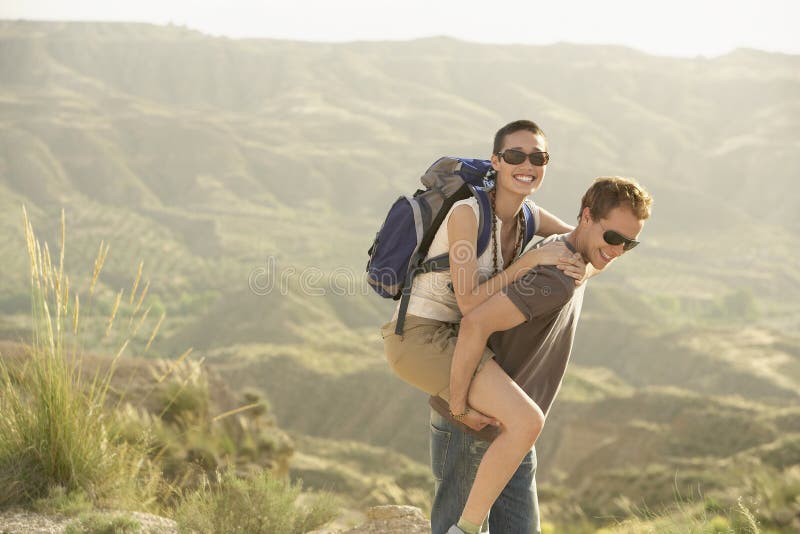 Hiking Couple Enjoying Piggyback Ride Through Mountains