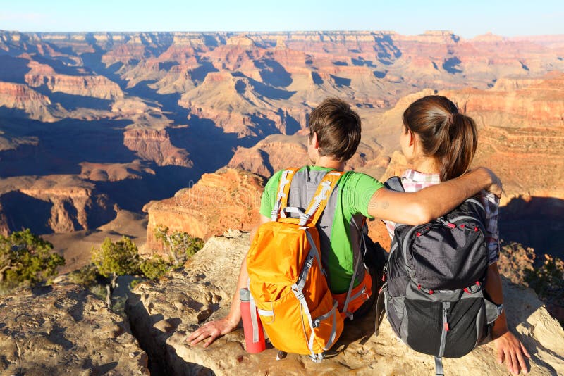 Hiking hikers in Grand Canyon enjoying view of nature landscape. Young couple relaxing during hike wearing backpacks on South Kaibab Trail, south rim of Grand Canyon, Arizona, USA.