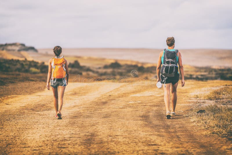 Hiking people walking on desert trail hike path with backpacks on mountain landscape nature. Hikers travel adventure