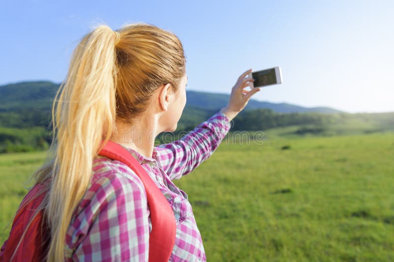 Hiking blonde woman taking photo with smart phone at mountains. Hiking blonde woman taking photo with smart phone at mountains.