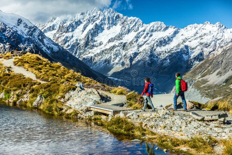 Hiking travel nature hikers in New Zealand mountains. Mount Cook landscape. Couple people walking on Sealy Tarns hike trail route towards Mueller Hut, famous tourist attraction.