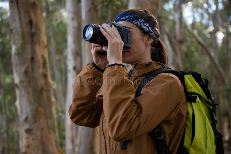 Hiker woman clicking a photo in forest