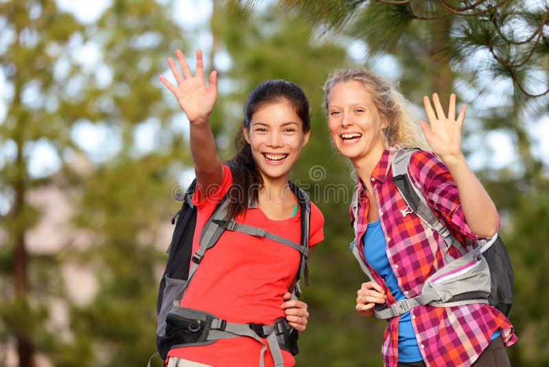 Hiking women waving hello smiling at camera happy