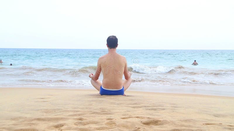 HIKKADUWA, SRI LANKA - FÉVRIER 2014 : La vue de la plage de Hikkaduwa tandis que les vagues éclaboussent et d'un homme médite prè banque de vidéos