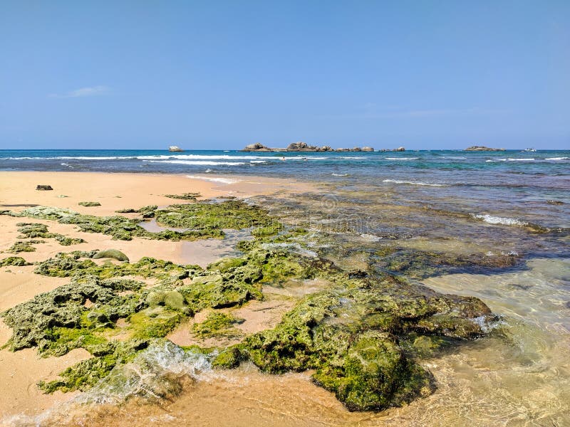 Hikkaduwa, Sri Lanka - March 8, 2022: Beautiful azure water of the Indian Ocean near the coral reef of Hikkaduwa beach. Stones and