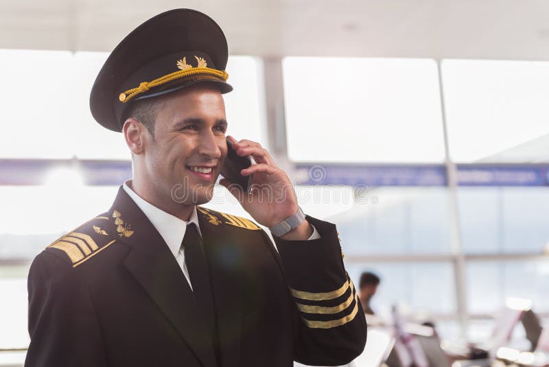 Hilarious smiling aviator using phone stock photo
