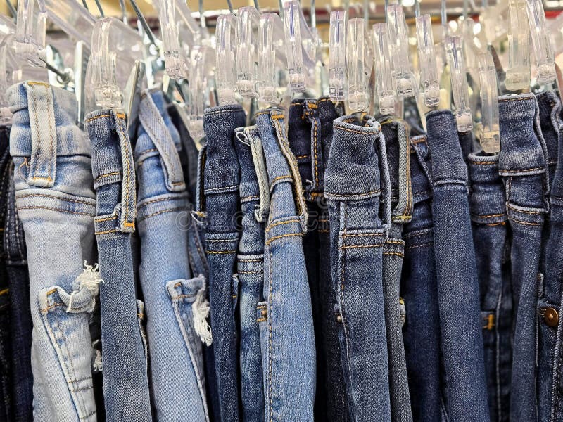 Close-up of distressed blue jeans clipped on clear plastic hangars in a boutique. Close-up of distressed blue jeans clipped on clear plastic hangars in a boutique