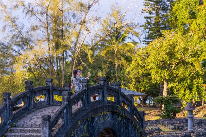 Beautiful Liliuokalani Park and Gardens in Hilo, Hawaii, on a rainy sunset. Young couple taking pictures