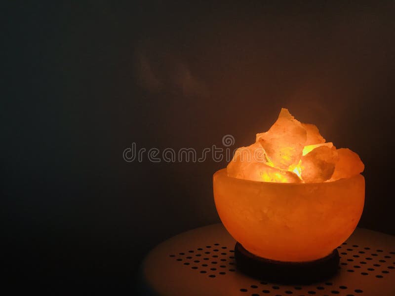 Himalayan salt lamp on a round table top with dark background. Himalayan salt lamp on a round table top with dark background.