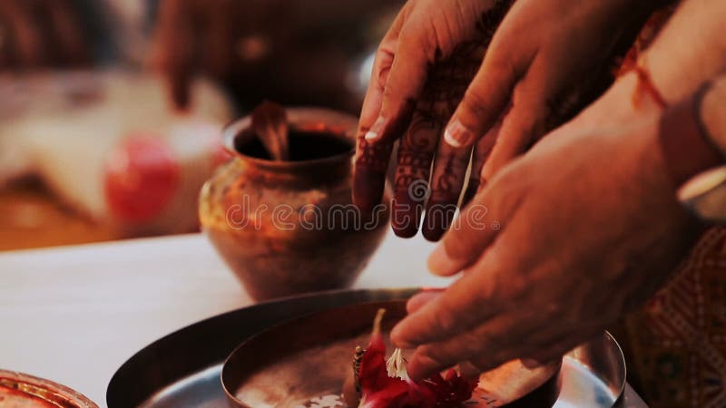 Hindu woman puts red petals on bronze plate