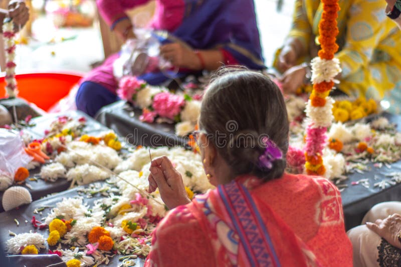 Hindu women weaving flower garlands, decorative wreath of flowers, at ISKCON Delhi Hindu temple of Lord Krishna, New Delhi, India. Hindu women weaving flower garlands, decorative wreath of flowers, at ISKCON Delhi Hindu temple of Lord Krishna, New Delhi, India