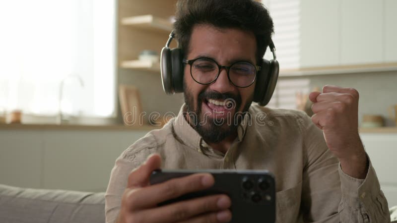 Hindú arabio sorprendió a un emocionado propietario de su casa con audífonos viendo un partido de video deporte en línea en su sma