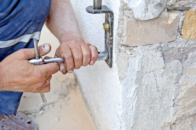 Closeup view of the handyman fixing the hinge on the wall. Closeup view of the handyman fixing the hinge on the wall.