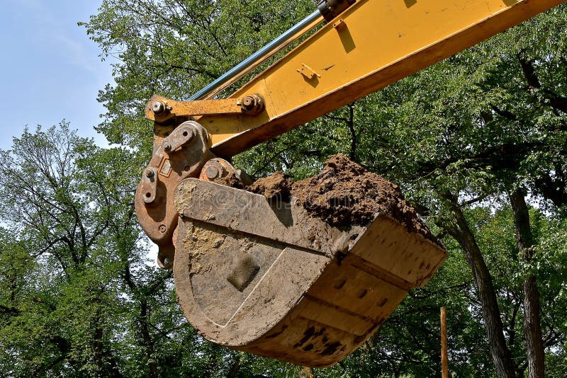 Hink av en backhoe som fylls med smuts arkivbild Hink av en backhoe som fylls med smuts arkivbild