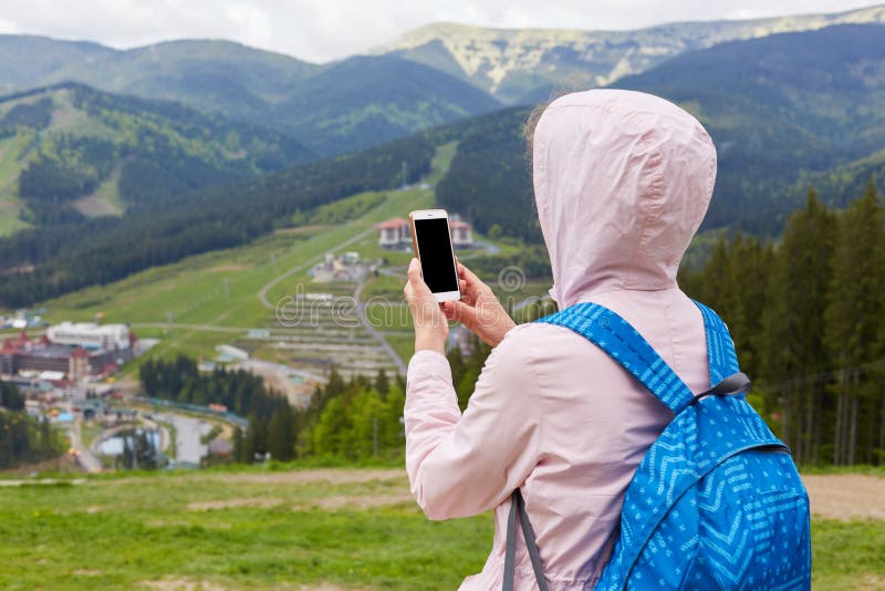 Hintere Ansicht der schlanken Frau ihren Smartphone in beiden Händen halten, die Fotos für Reiseblog machend und online suchen na lizenzfreies stockfoto Hintere Ansicht der schlanken Frau ihren Smartphone in beiden Händen halten, die Fotos für Reiseblog machend und online suchen na lizenzfreies stockfoto