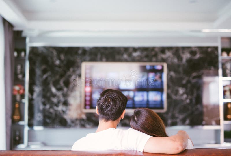 Hintere Ansicht des aufpassenden Fernsehens der Paare im Wohnzimmer lizenzfreie stockfotos