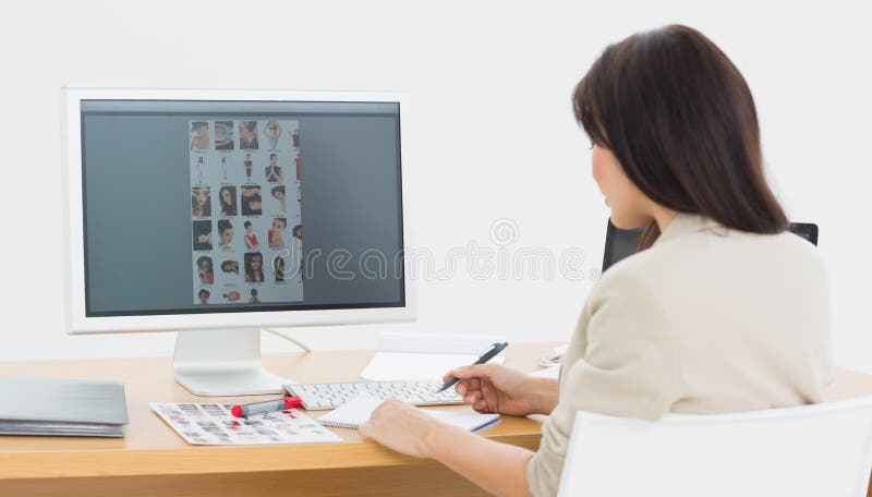 Hintere Ansicht eines Künstlers am Schreibtisch mit Computer im Büro stockbild Hintere Ansicht eines Künstlers am Schreibtisch mit Computer im Büro stockbild