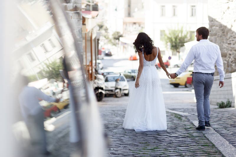 Hintere Ansicht eines romantischen Paares von Jungvermähltenwege auf der alten Straße Griechenland Hochzeit in Griechenland lizenzfreie stockbilder Hintere Ansicht eines romantischen Paares von Jungvermähltenwege auf der alten Straße Griechenland Hochzeit in Griechenland lizenzfreie stockbilder