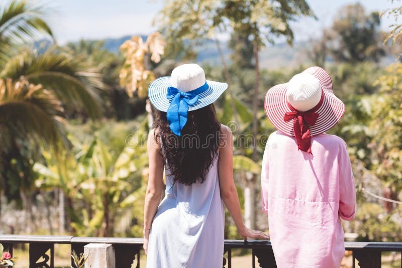 Hintere hintere Ansicht von junge Frauen-Paar-tragenden Hüten über schöner tropischer Landschaft stockfoto Hintere hintere Ansicht von junge Frauen-Paar-tragenden Hüten über schöner tropischer Landschaft stockfoto