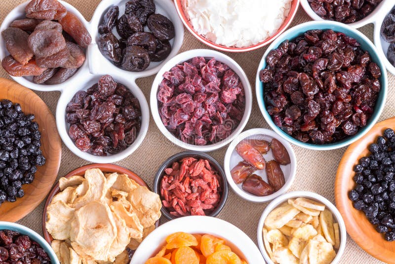 Background pattern and texture of assorted dried fruit displayed in individual round bowls including goji berries, cranberries, apple, coconut, apricot, banana and dates, close up top view on burlap. Background pattern and texture of assorted dried fruit displayed in individual round bowls including goji berries, cranberries, apple, coconut, apricot, banana and dates, close up top view on burlap