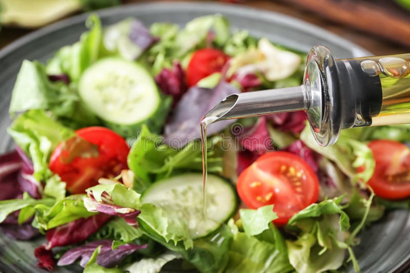 Hinzufügen des Olivenöls geschmackvollem Gemüsesalat, Nahaufnahme stockbild Hinzufügen des Olivenöls geschmackvollem Gemüsesalat, Nahaufnahme stockbild