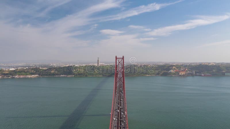 Hiperlapso aéreo del tráfico a través del puente ponte 25 de abril en lisboa con santuario de cristo rey en el almacen de video