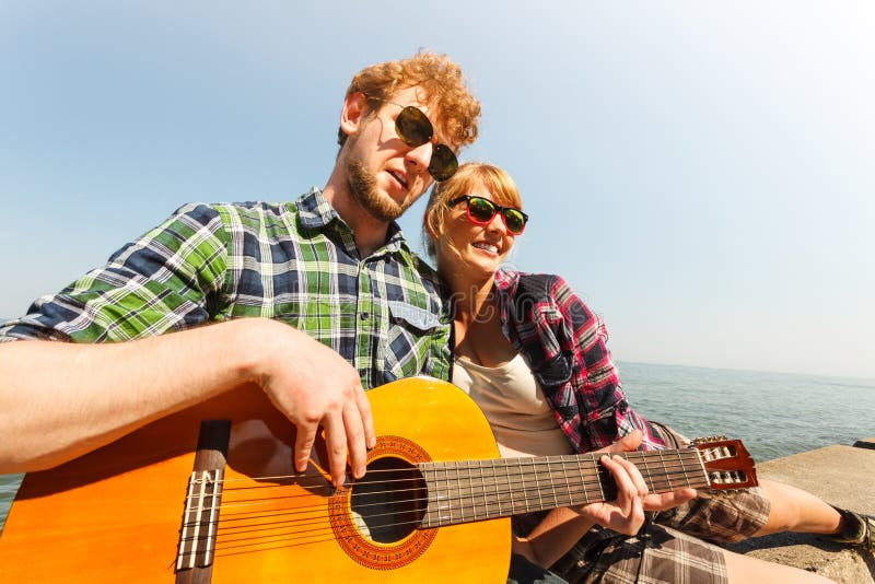 Hippie des jungen Mannes, der Gitarre für Frau spielt stockbild Hippie des jungen Mannes, der Gitarre für Frau spielt stockbild