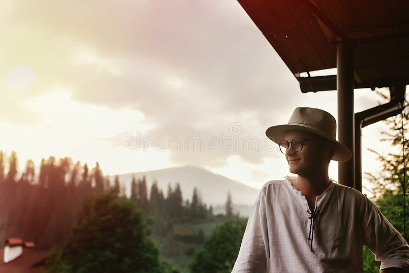 Hippie-Mann, der auf dem Portal des Holzhauses mounta betrachtend steht stockfoto Hippie-Mann, der auf dem Portal des Holzhauses mounta betrachtend steht stockfoto
