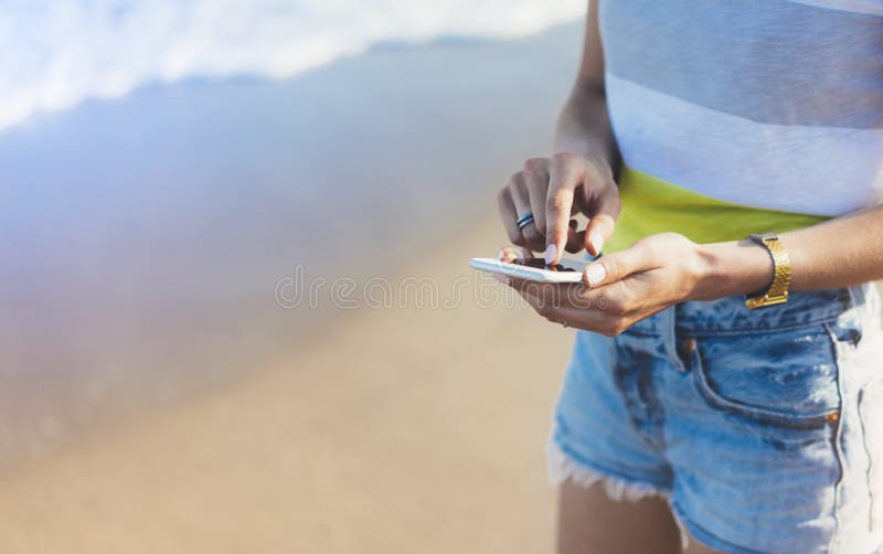 Hippie-Mädchengriff auf intelligentem Telefongerät in der Sandküstenlinie, verspotten oben vom leeren Bildschirm Reisender, der i lizenzfreies stockfoto