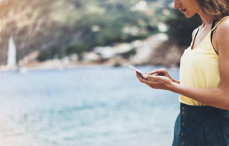 Hippie-Mädchengriff auf intelligentem Telefongerät in der Sonnensandküstenlinie, verspotten oben Reisender, der im weiblichen Han lizenzfreies stockfoto