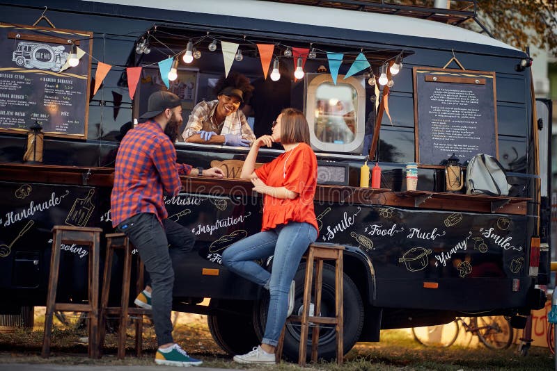 Hipster couple ordering from food truck on the street; Urban lifestyle concept. Hipster couple ordering from food truck on the street; Urban lifestyle concept