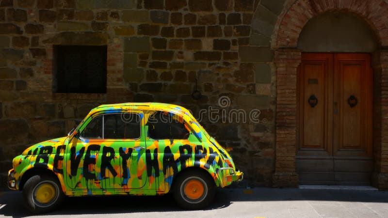 Hippy auto prima di una facciata in mattoni a vista nella città di Montalcino.