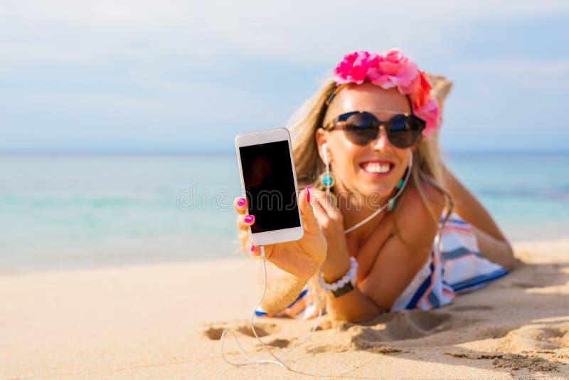 Hipster girl showing something on the phone while lying on the beach, mockup for screen design.