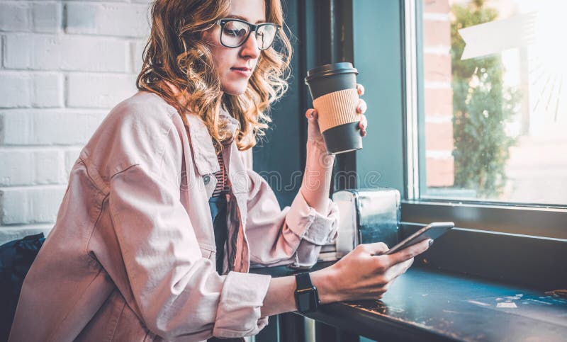 Hipster girl sitting in cafe at black table, drinking coffee and using smartphone. Businesswoman working online. stock photos Hipster girl sitting in cafe at black table, drinking coffee and using smartphone. Businesswoman working online. stock photos