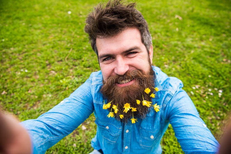 Hipster on happy face taking selfie photo. Man with beard enjoys spring, green meadow background, defocused. Natural royalty free stock photography Hipster on happy face taking selfie photo. Man with beard enjoys spring, green meadow background, defocused. Natural royalty free stock photography