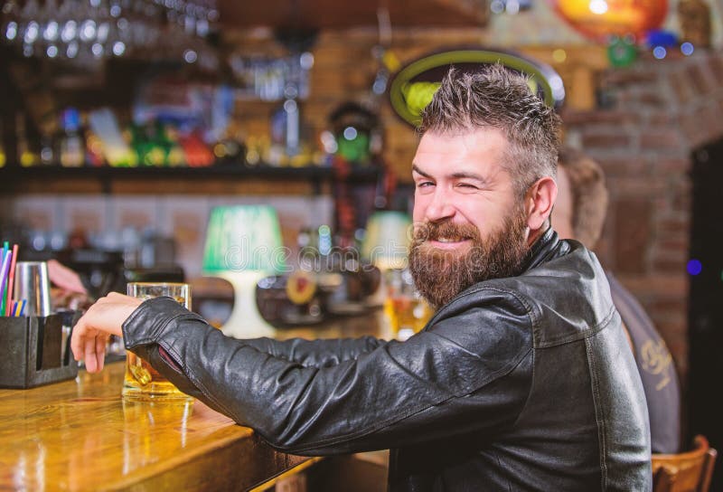 Hipster het ontspannen bij bar met bier De brutale hipster gebaarde mens zit bij barteller drinkt bier De drank van de ordealcoho royalty-vrije stock foto Hipster het ontspannen bij bar met bier De brutale hipster gebaarde mens zit bij barteller drinkt bier De drank van de ordealcoho royalty-vrije stock foto