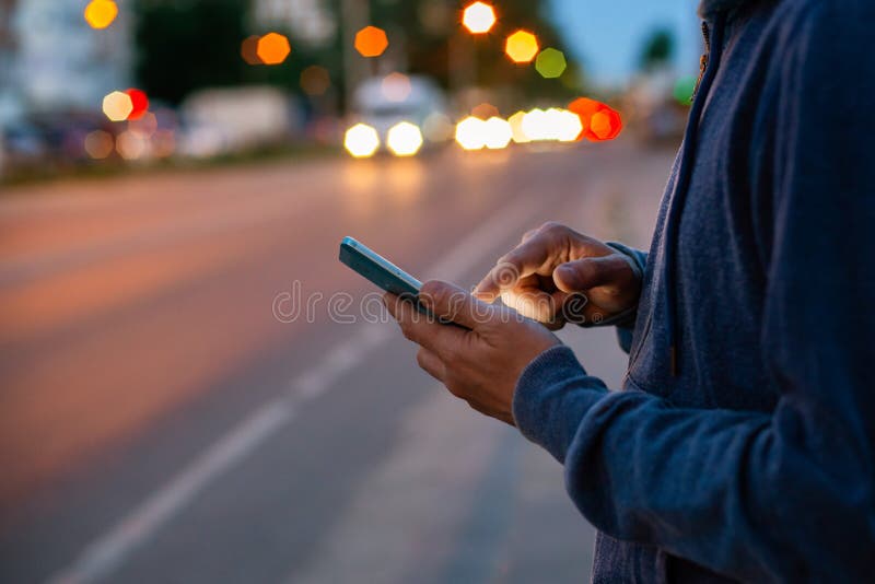 Hipster man talking on a mobile phone at night in the city against the background of bokeh lights