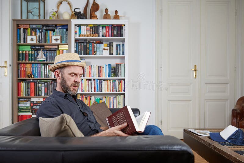 Hipster med hatten som hemma läser en bok royaltyfri foto Hipster med hatten som hemma läser en bok royaltyfri foto
