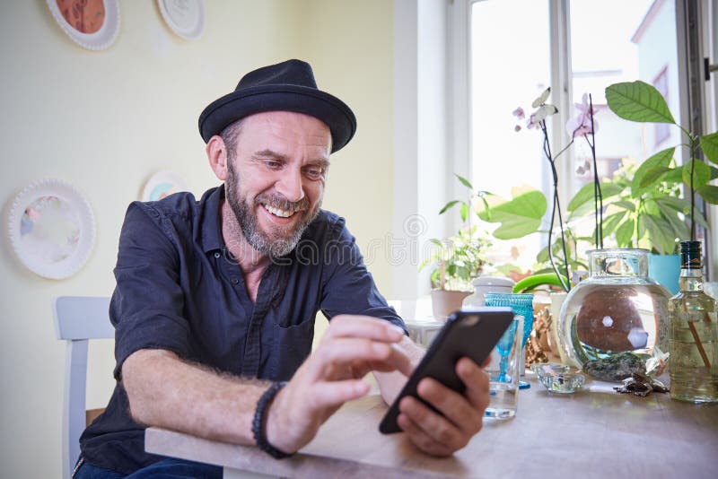 Hipster som ser telefonen till lyckligt skratta för kamera royaltyfri foto Hipster som ser telefonen till lyckligt skratta för kamera royaltyfri foto