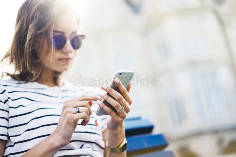 Hipster texting message on smartphone or technology, mockup of blank screen. Girl using cellphone on building castle background