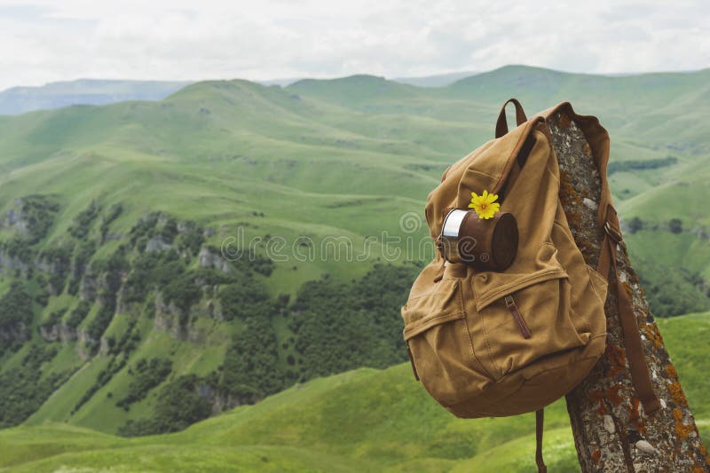 Hipster yellow vintage backpack with a mug fixed on it with a mug close-up front view. Traveler`s travel bag in the