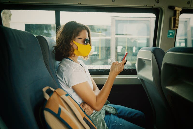 Hipster young girl in a protective mask on her face in a public transport bus with a smartphone in her hands stock images Hipster young girl in a protective mask on her face in a public transport bus with a smartphone in her hands stock images