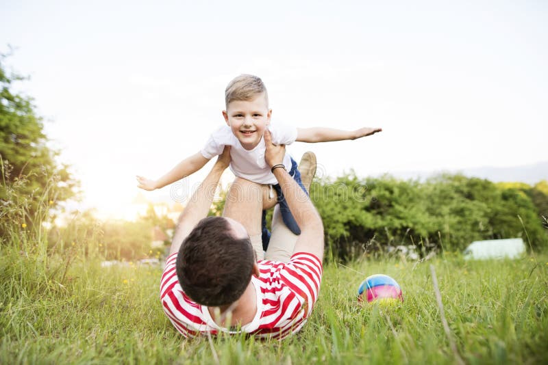 Hipsterfader och liten son på grön äng solig dagsommar fotografering för bildbyråer Hipsterfader och liten son på grön äng solig dagsommar fotografering för bildbyråer