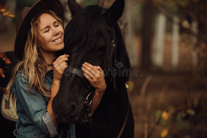 Hipsterflicka med en häst i le för trän fotografering för bildbyråer Hipsterflicka med en häst i le för trän fotografering för bildbyråer
