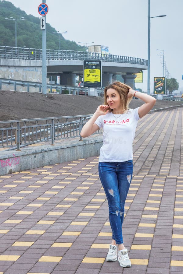 Hipstermeisje die lege witte t-shirt, jeans en honkbal GLB het stellen tegen ruwe straatmuur, volledig lengteportret dragen, stock foto Hipstermeisje die lege witte t-shirt, jeans en honkbal GLB het stellen tegen ruwe straatmuur, volledig lengteportret dragen, stock foto