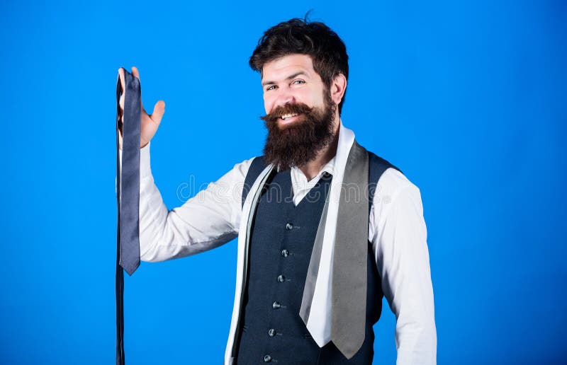 His favorite tie is here. Businessman in fashionable hipster style. Fashion model with fashionable look. Fashionable man. Bearded man holding necktie. Brutal guy choosing fashionable classy accessory.
