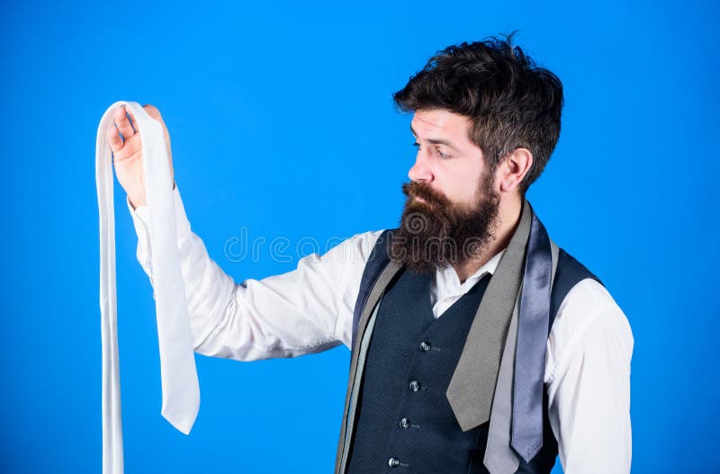 His wardrobe presents his style sense. Bearded man choosing a necktie from his wardrobe. Stylish mens wardrobe for business or formal occasions. Creating a very effective formal wardrobe background.